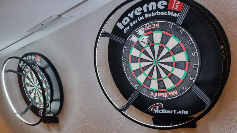Zwei Dartscheiben an der Wand, darüber das Logo der Taverne